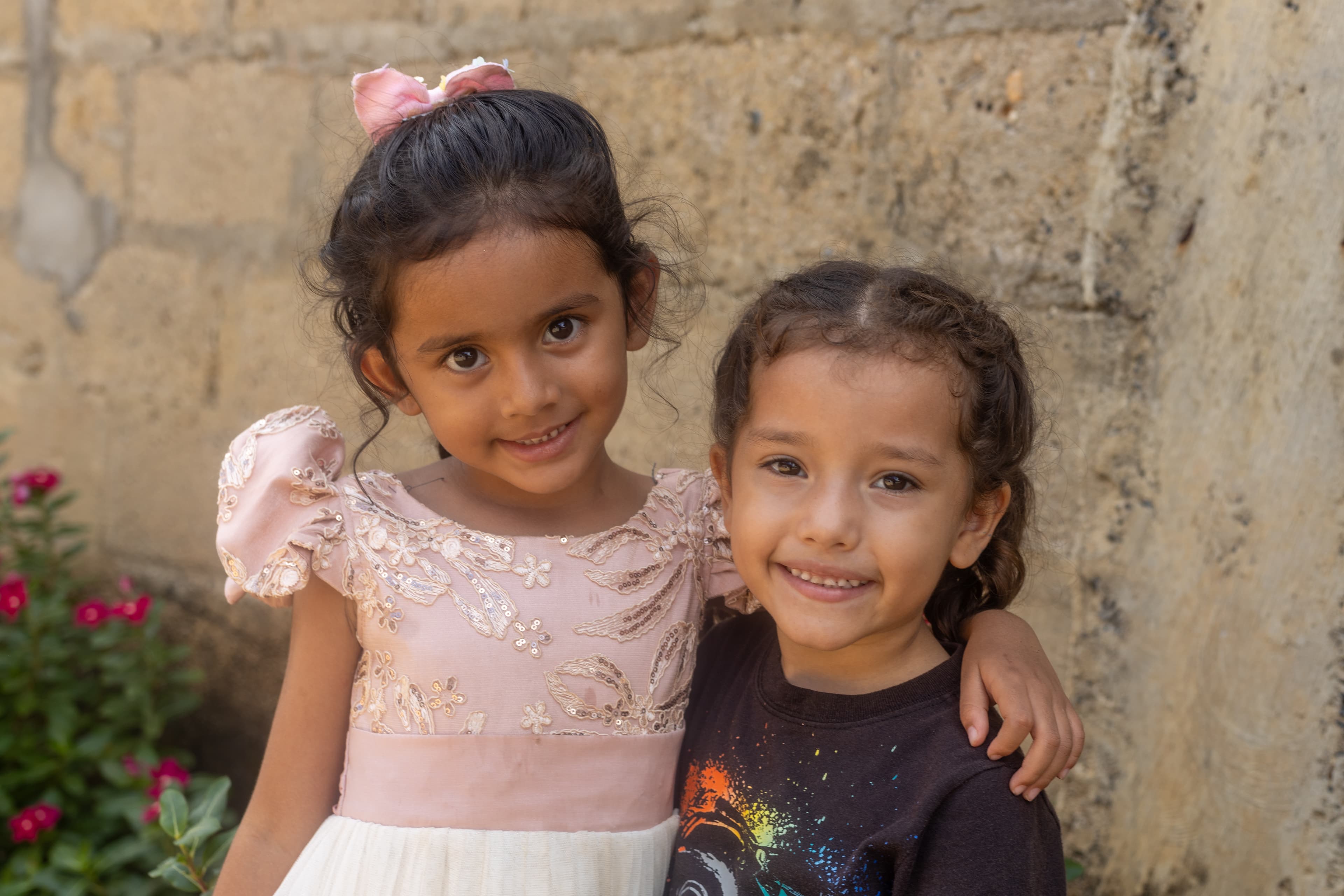 Two young Colombian girls embrace and smile for the camera.