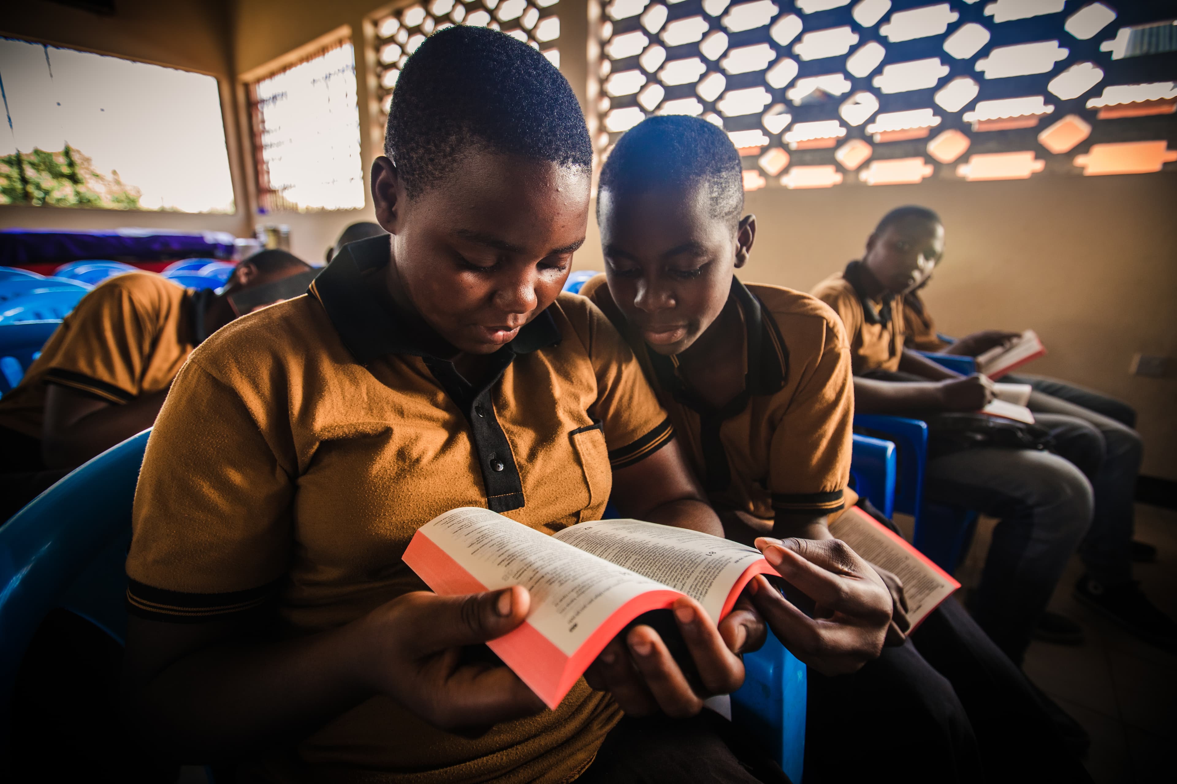 Two young girls are sitting and reading a bible together.