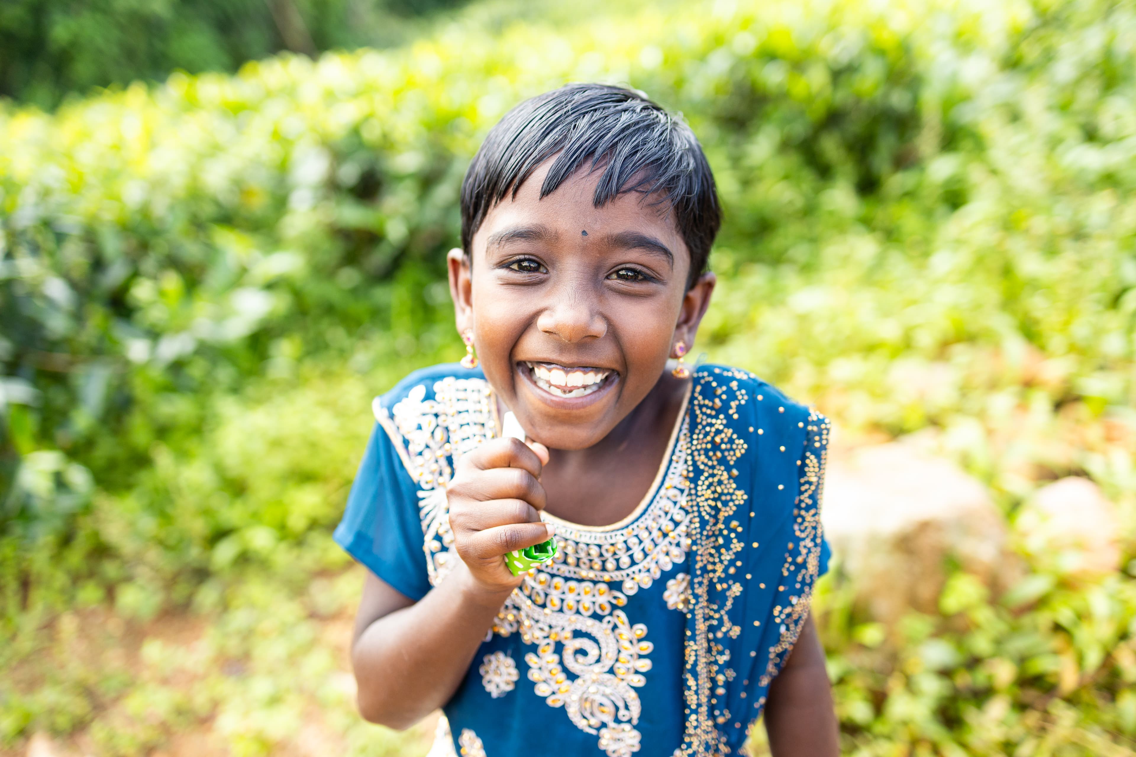 A young girl is smiling at the camera and laughing.