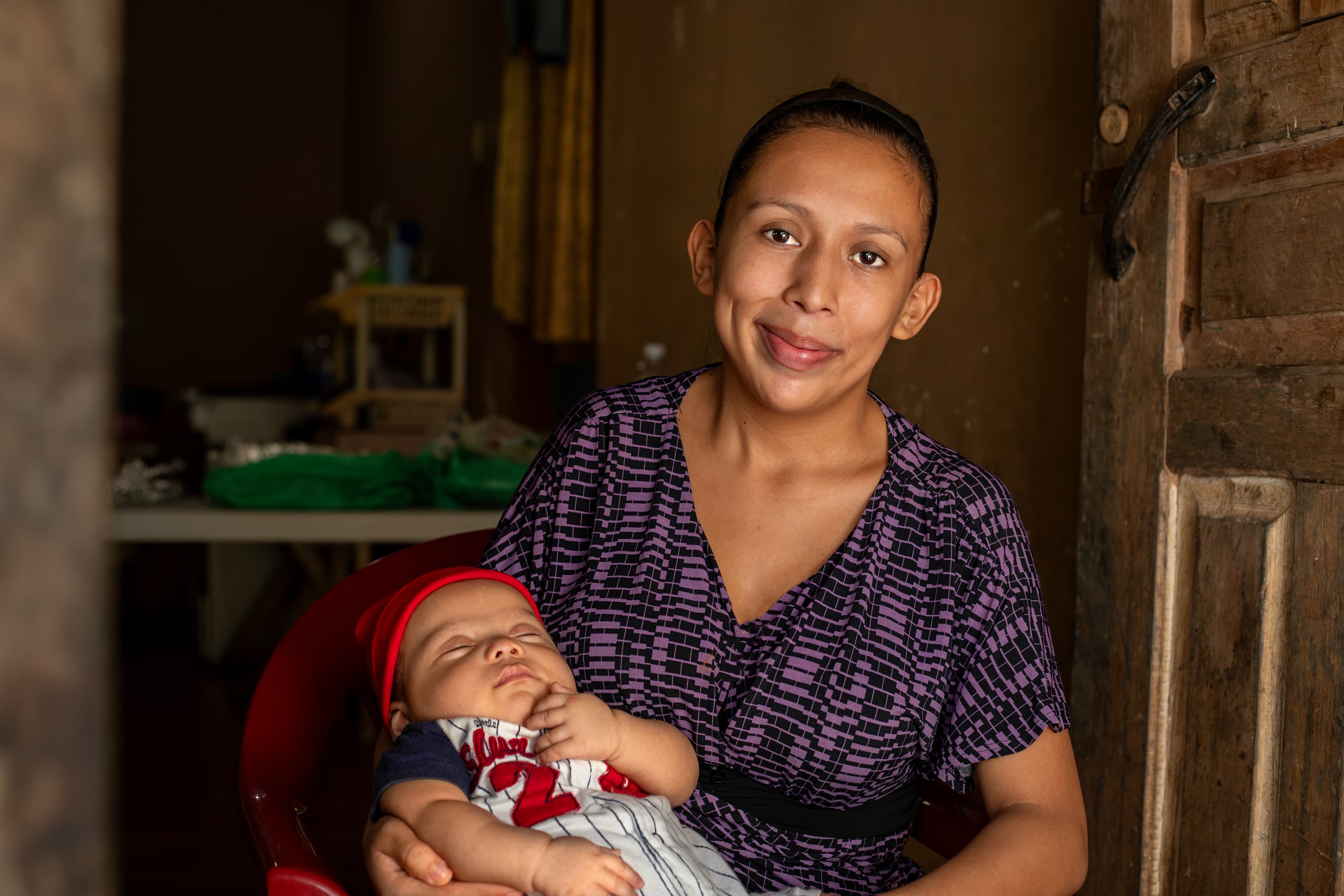 A mom holds her infant daughter while smiling for the camera.