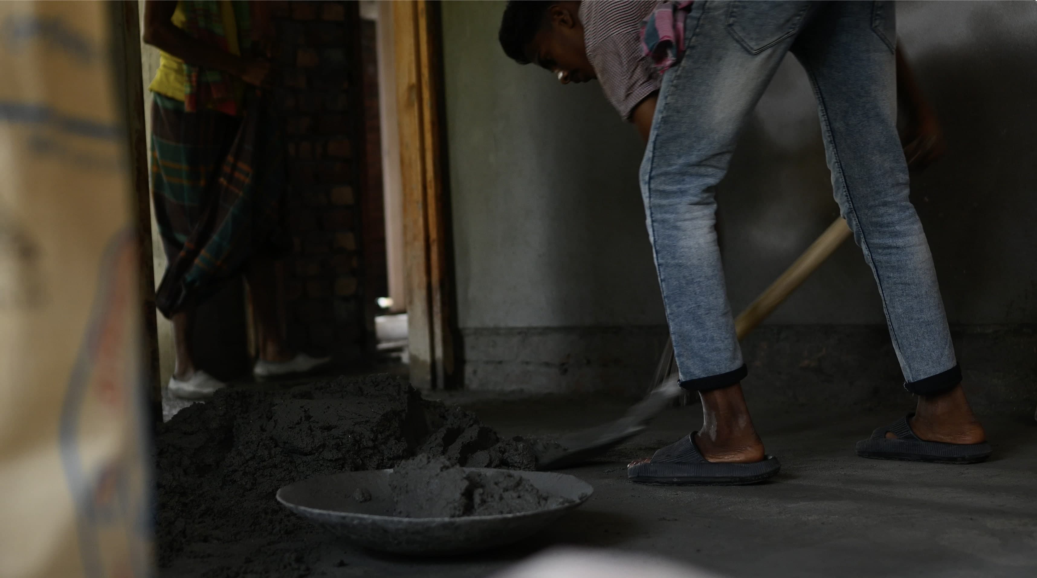 A young boy shovels concrete into a bowl.