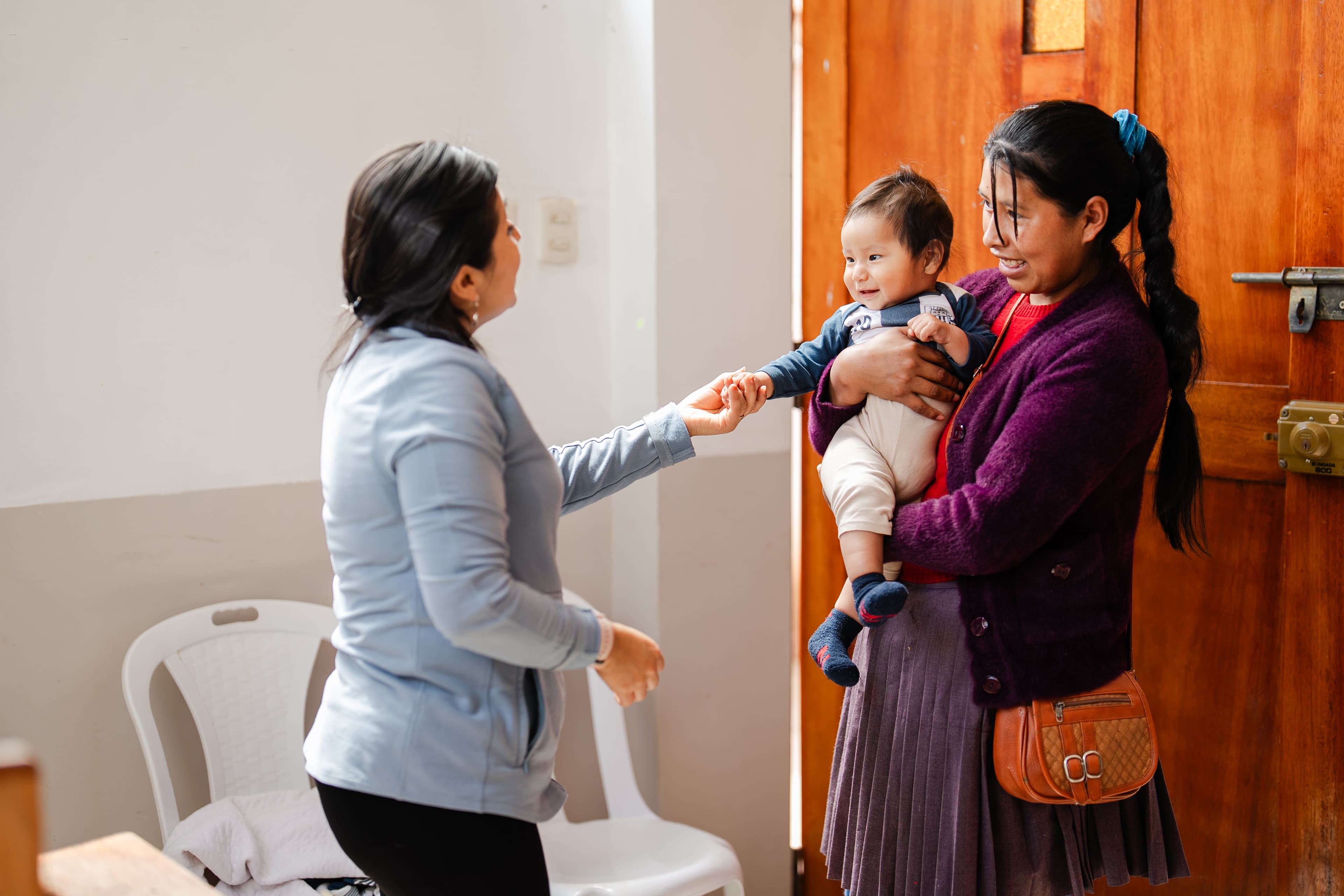 A baby and her mother are smiling at the survival coordinator at church.