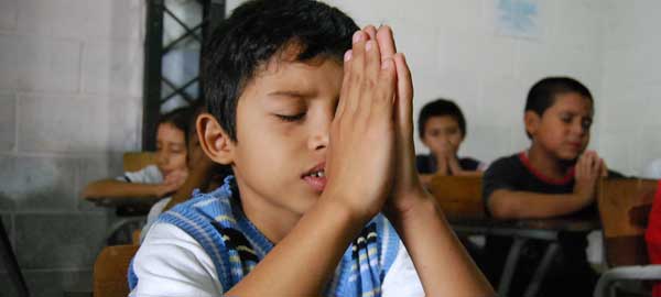 A young boy praying in school