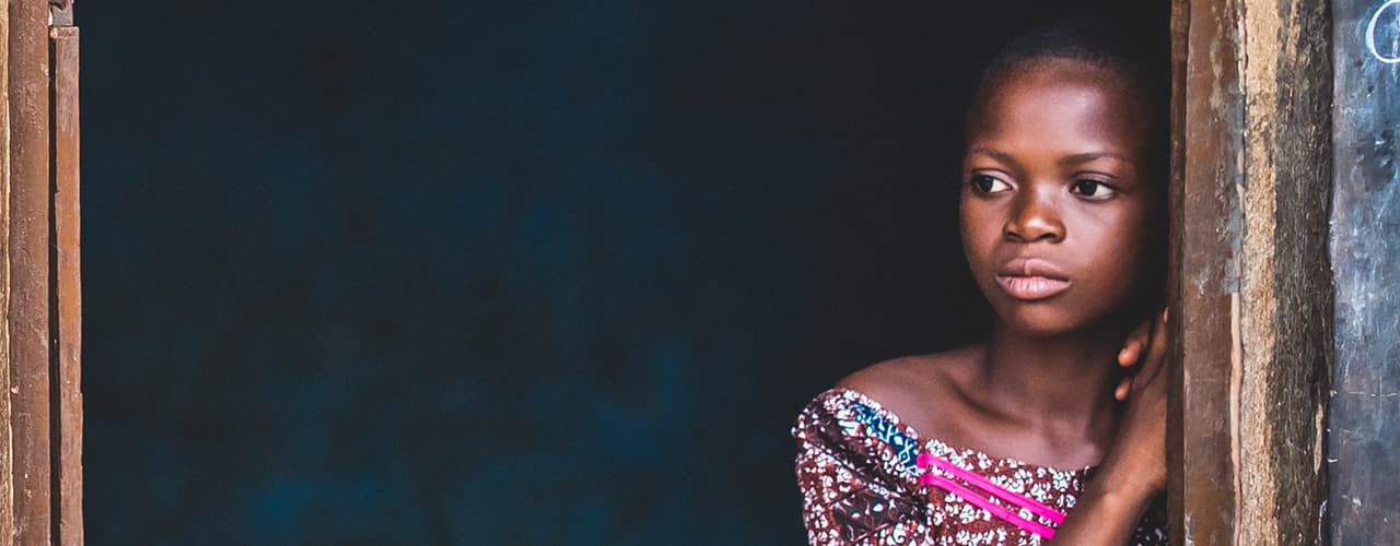 Girl leaning on a doorpost looking into the distance.