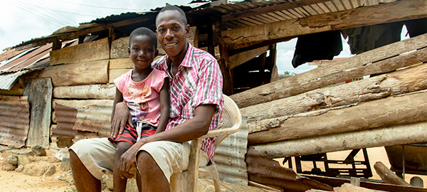 A man and child sit in front of a home