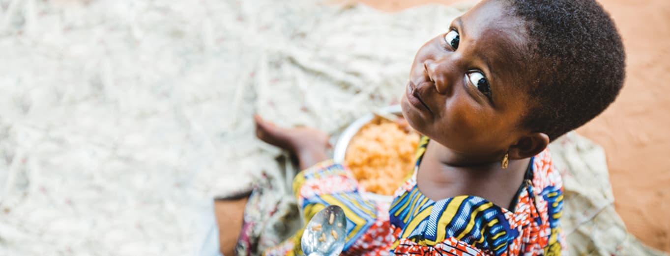 Minister to a malnourished child by giving food.