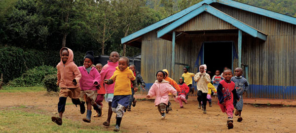 Children running in a field outside the local church