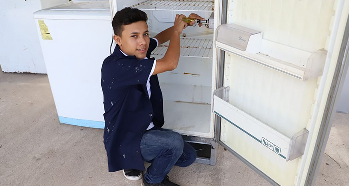Julian smiles in front of a refrigerator