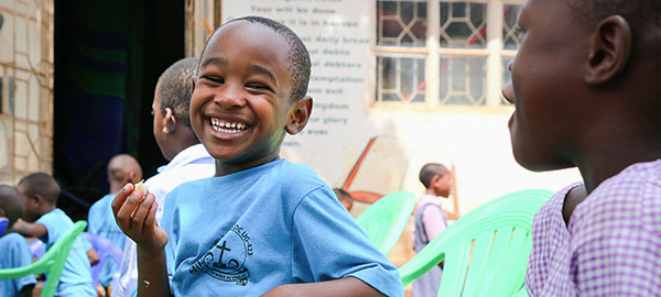 A boy smiles with other children at a Compassion center